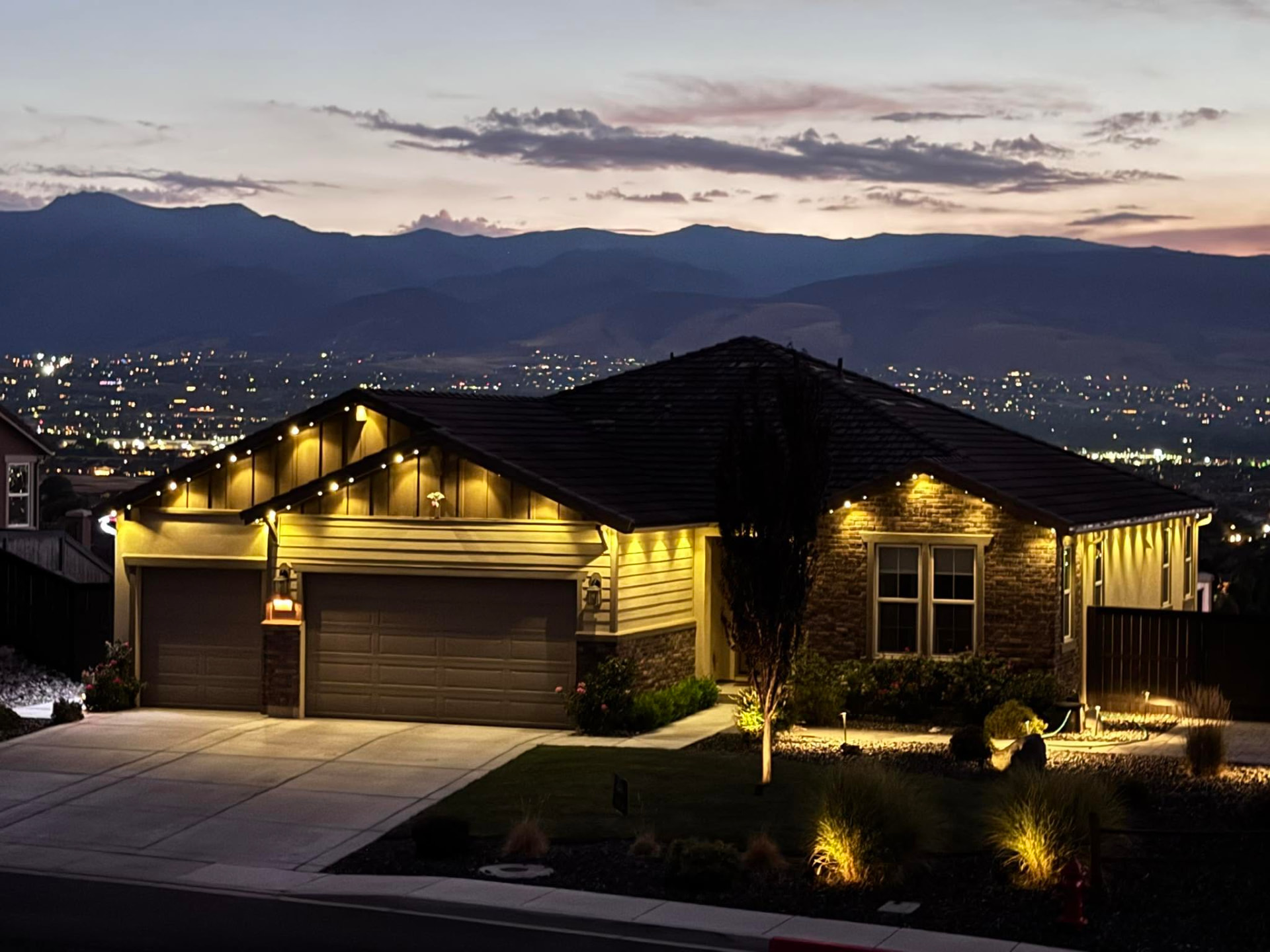 Hillside home with warm permanent lighting and city views
